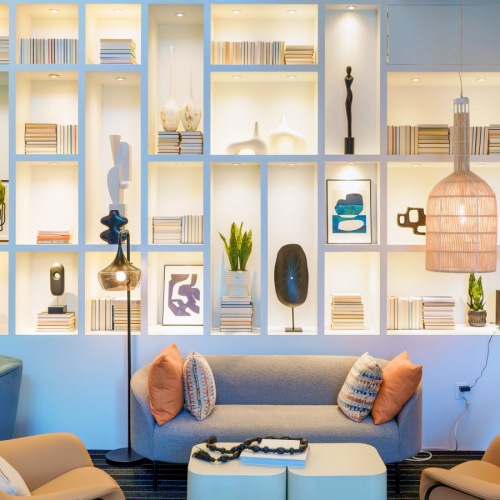 Lobby and lounge at our apartments in Arlington, featuring cushioned chairs, a long dining room table, and bookshelves.