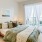 Model bedroom at our apartments in Arlington, featuring wood furniture, a large window, and wood laminate floors.